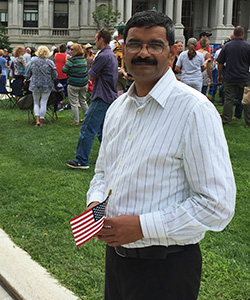 Arif David standing in front of Capitol, small American flag in hand