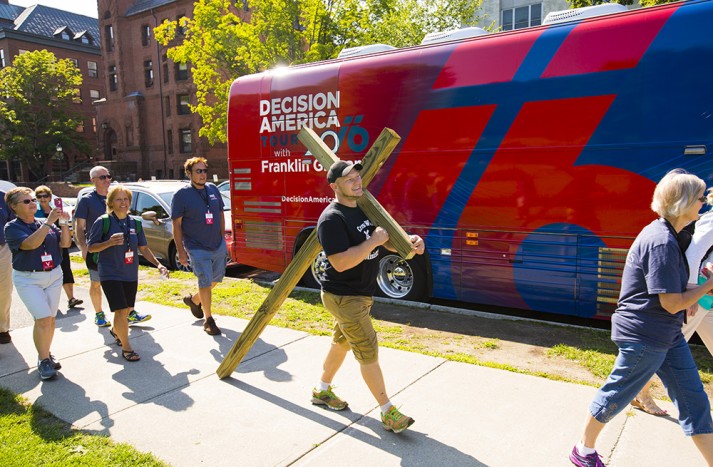 Man carrying cross by Decision America bus