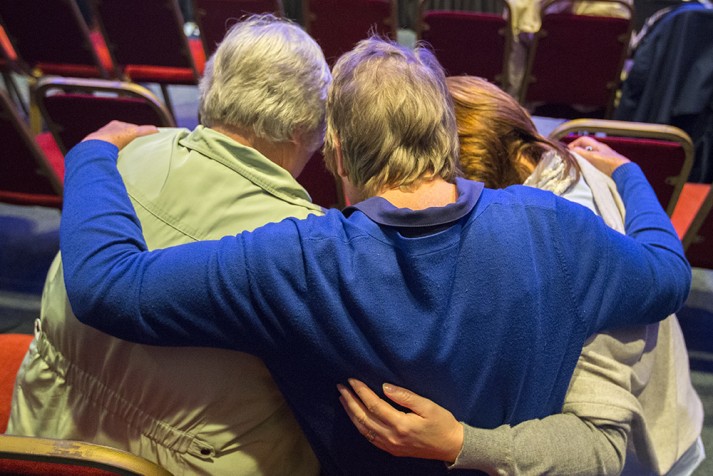 Mother, counselor and daughter huddled in prayer, arms around each other