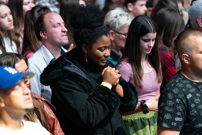 Woman praying at the God Loves You Tour in Krakow, Poland