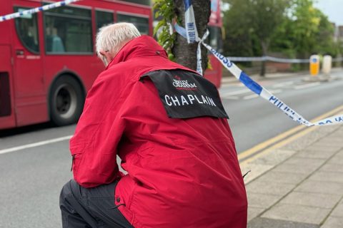 A chaplain kneels near the scene of the attack in Hainault