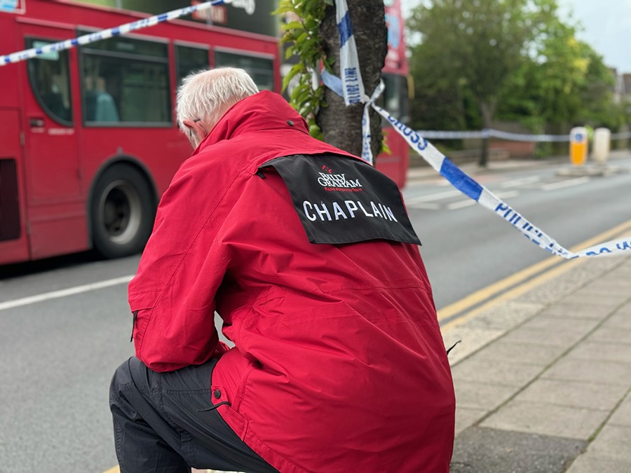 A Billy Graham Rapid Response Team chaplain kneels near the scene of the attack in Hainault