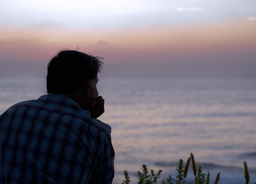 Man sits looking out into water