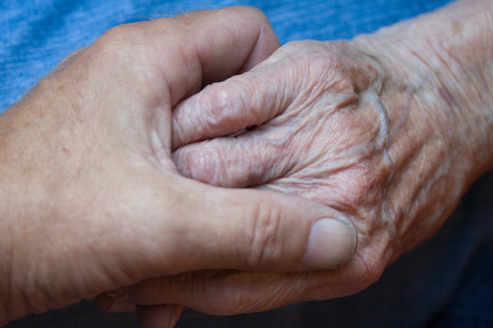 elderly woman holds son's hand