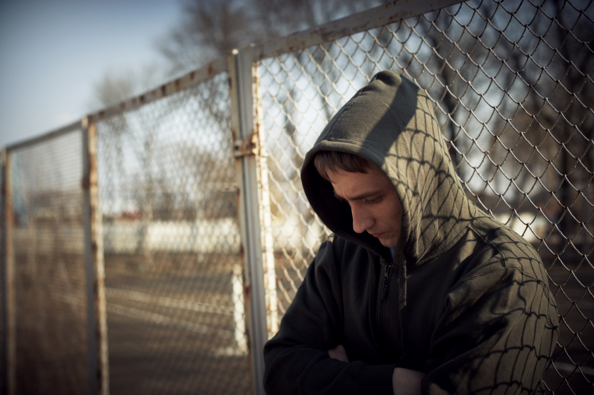 guy in hoodie against fence