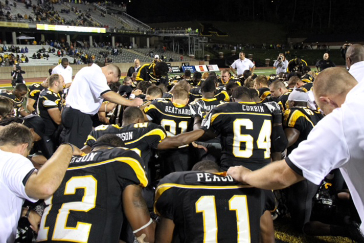 Coaches and players from the Appalachian State University football team gather for prayer.