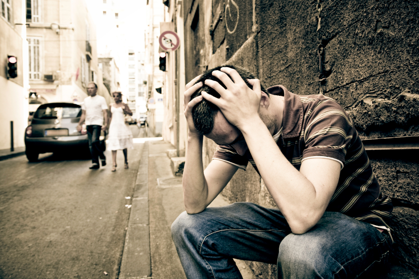 Man crouched over holding head