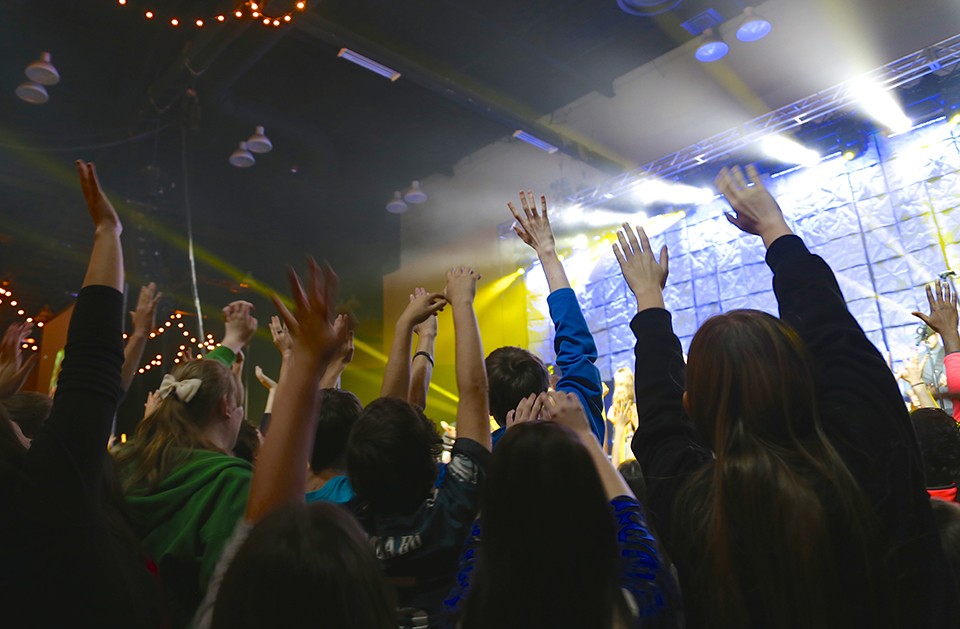 teens raising hands at concert