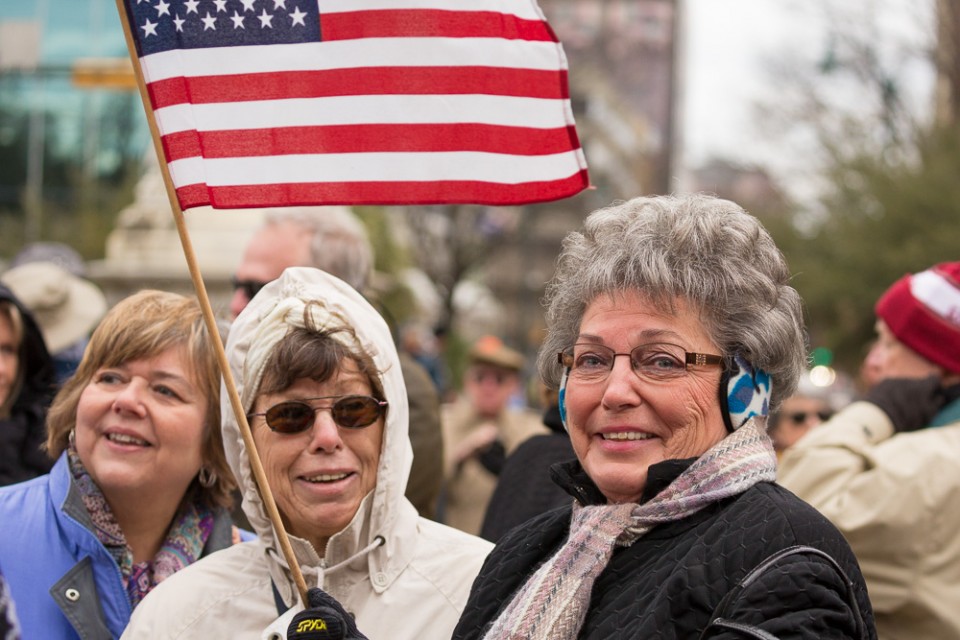 2 women dressed warm, with flag