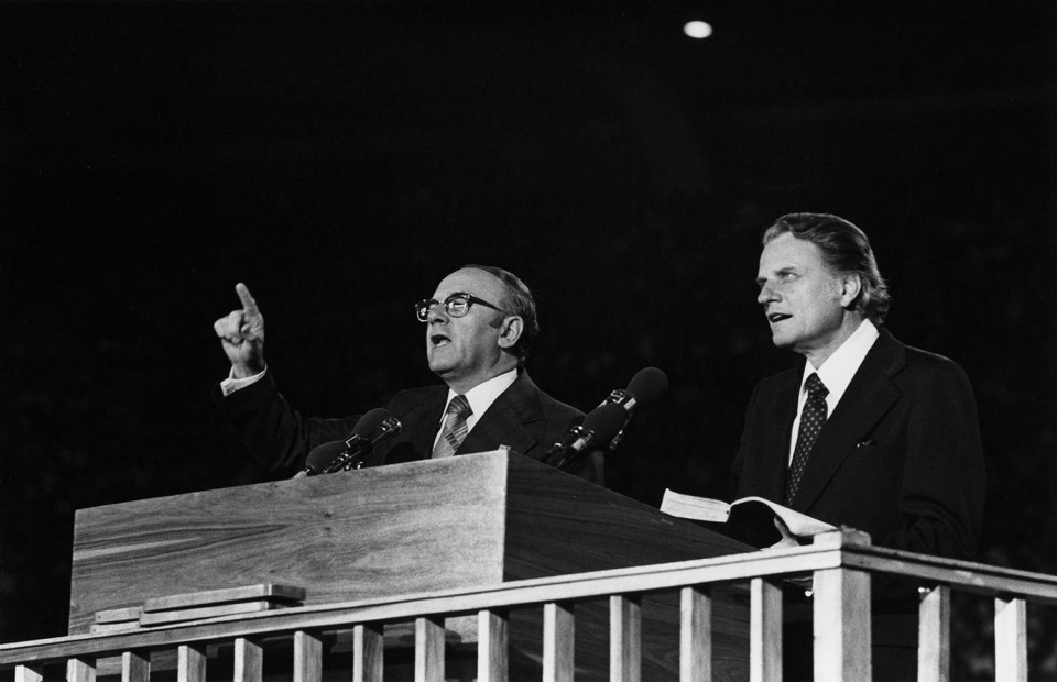 two men speaking to a crowd