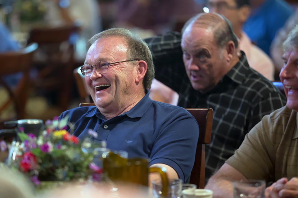 Man laughing as he listens to speaker