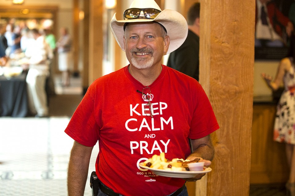 Man wearing cowboy hat carrying plate of food
