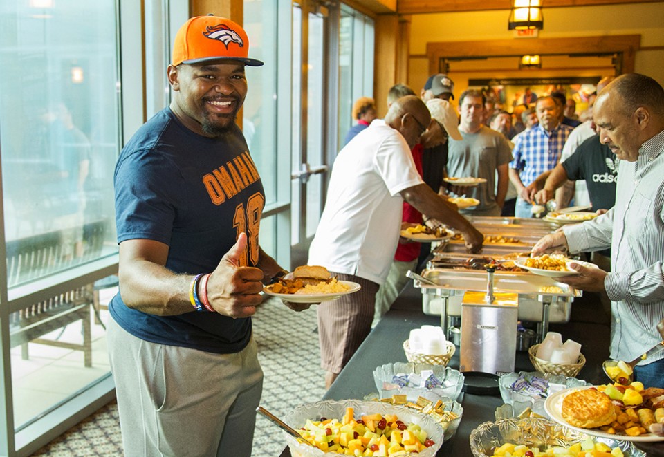 Man holding plate of food in buffet line giving thumbs up