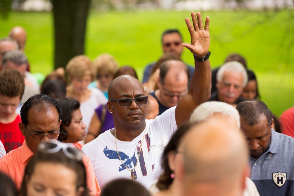 Man with USA t-shirt in crowd. Lifting hand to God