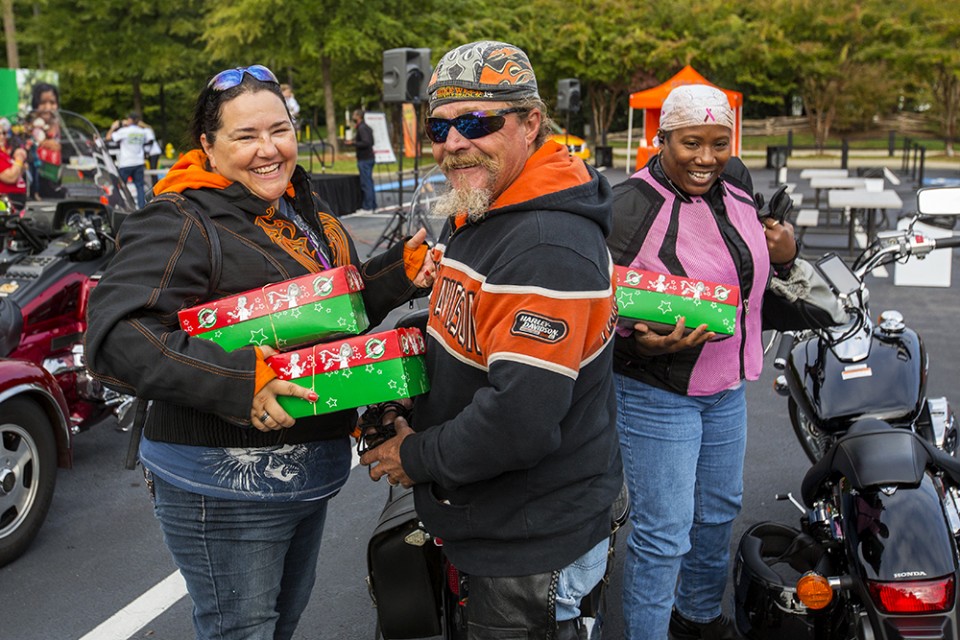 Bikers holding green and red shoeboxes, smiling