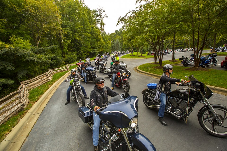 Lines of bikers ride through parking lot