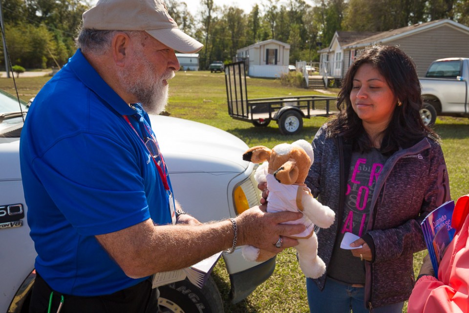 Chaplain hands stuffed animal (dog) to flood victim for her daughter