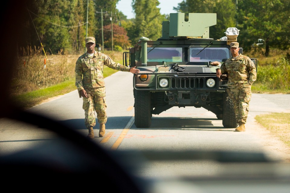 Two National Guard members stand beside Humvee
