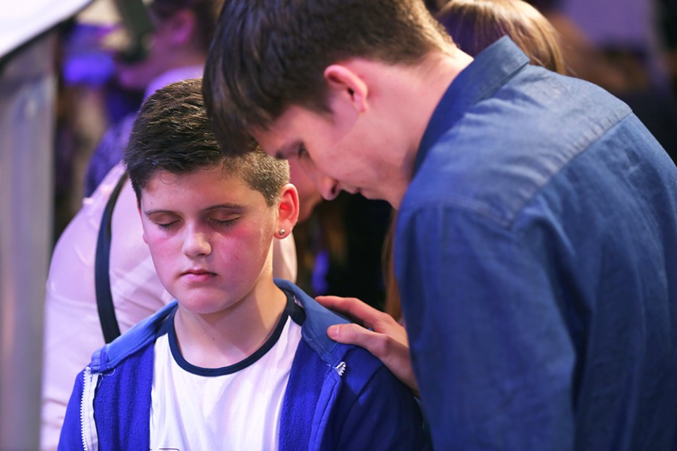 young man prays for boy