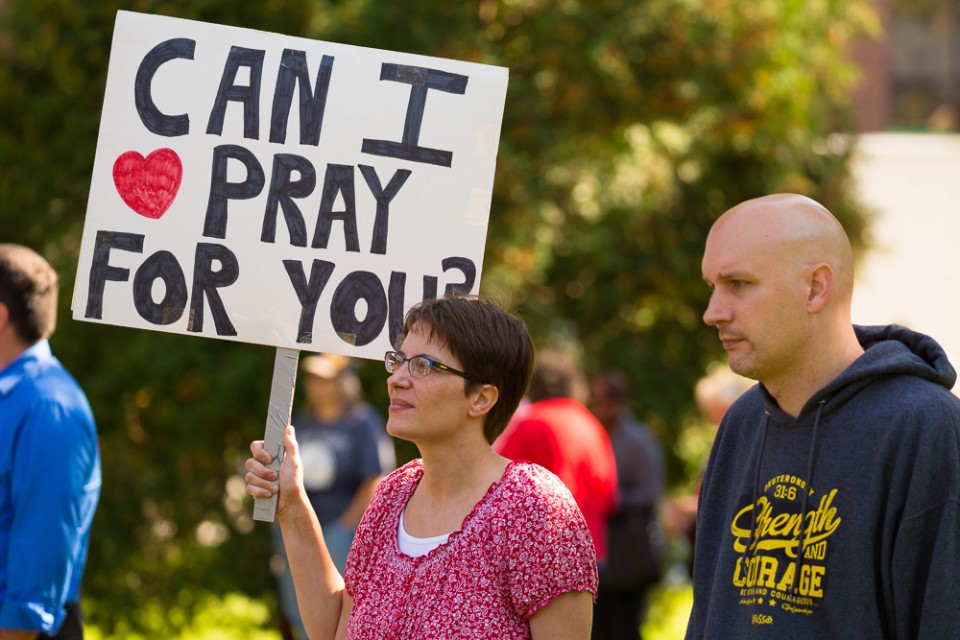 Woman holding sign that says "Can I pray for you?"