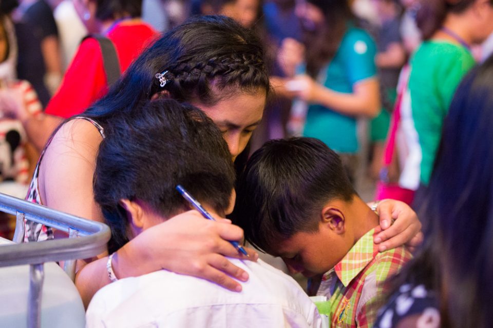Counselor prays with two young boys