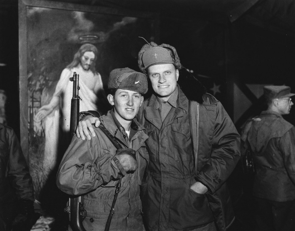 Billy Graham with arm around soldier. Picture of Jesus in background.