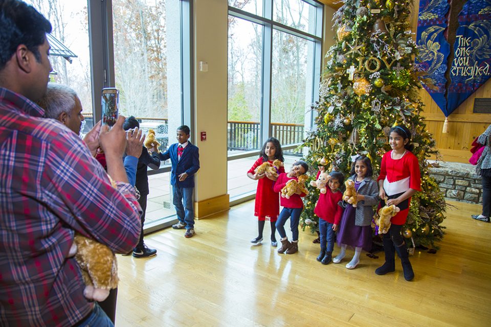 A family posing for picture in front of large Christmas tree