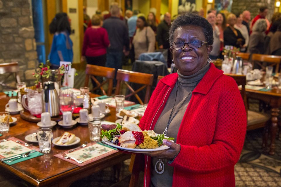Woman holding full plate of food, smiling