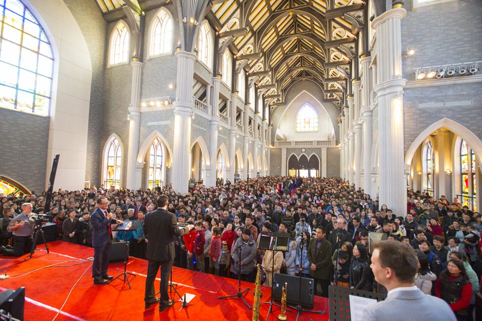 Wide shot of crowd with Will Graham and interpreter from the back