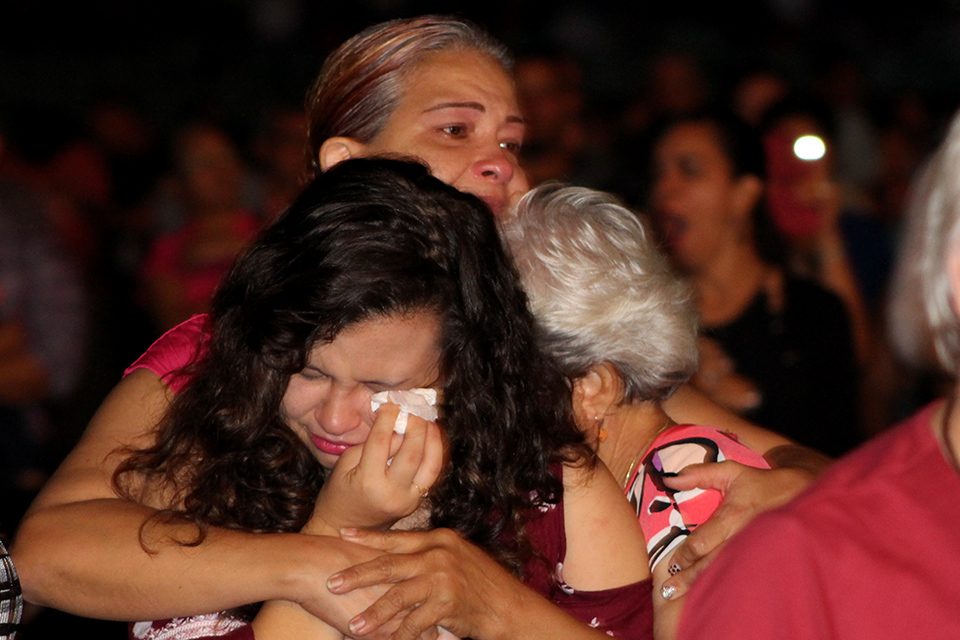Three women hugging, one wiping away tears