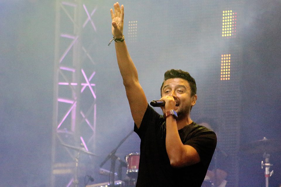 Alex Campos singing with hand raised