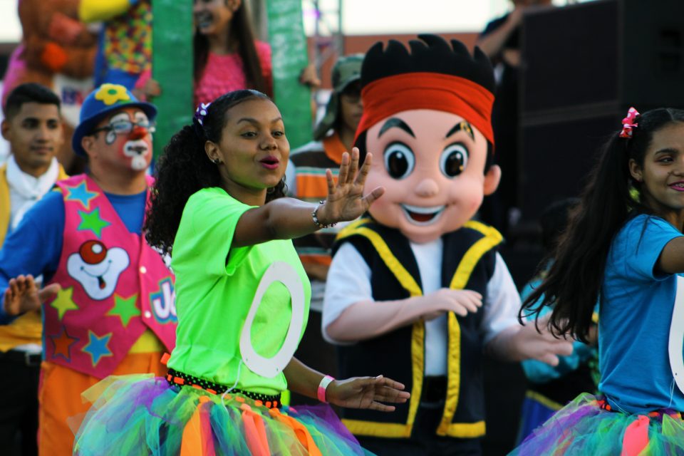 Young girl in bright colored skirt dancing; huge animated figure