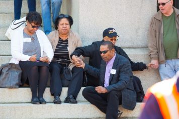 People on steps of Maryland capital holding hands and praying