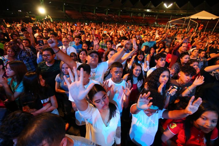 Youth in big crowd, arms raised