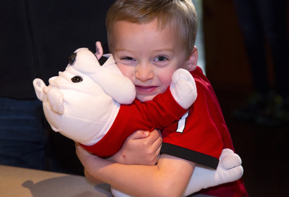 Little boy hugging Georgia Bulldog stuffed animal