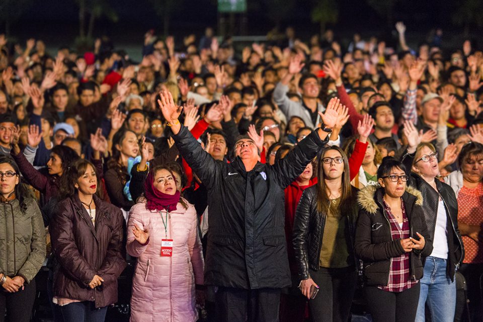 Man in crowd with arms raised in worship to God