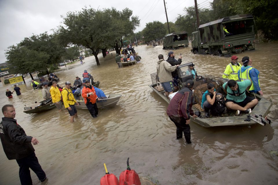 People in boats on flooded streets; rescuers