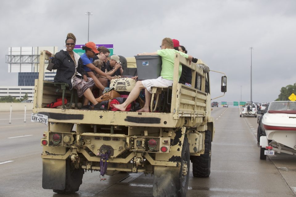 Military vehicle driving down street with evacuees on the open-air back