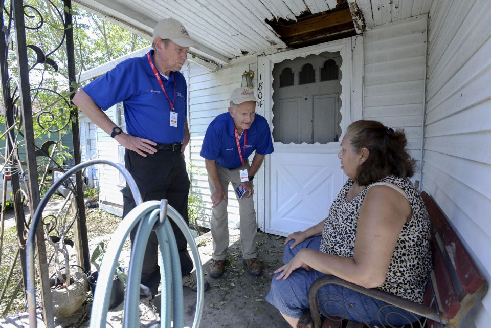 Woman sitting on porch as two chaplains listen