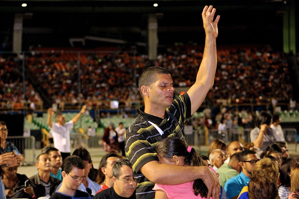 Man worshipping with one hand raised; hugging young girl