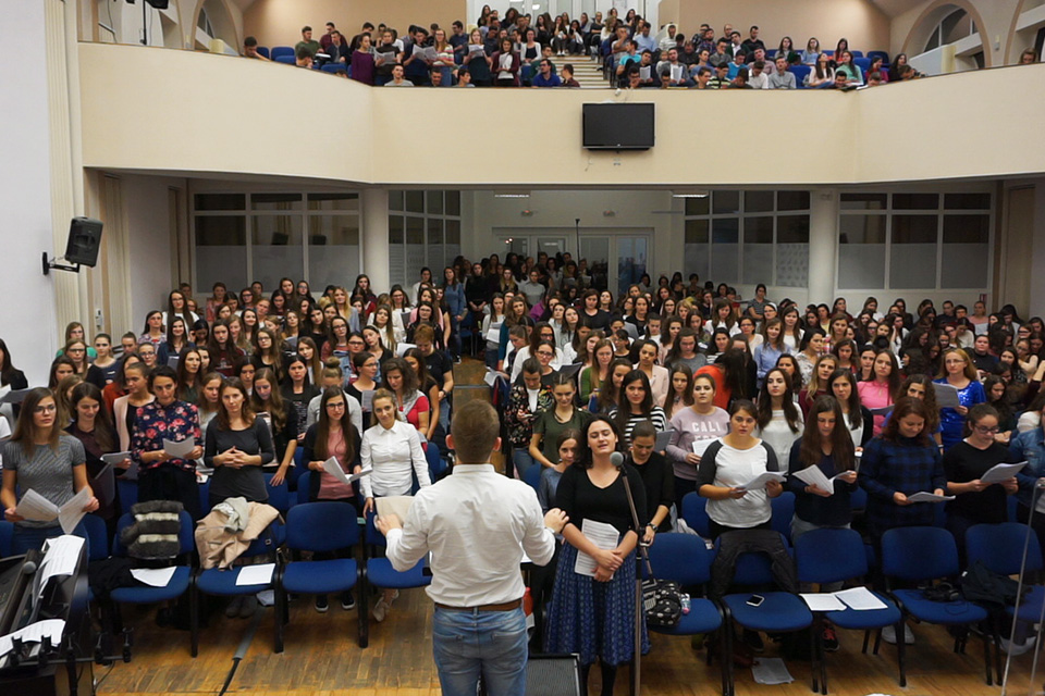 Man in foreground, directing large youth choir