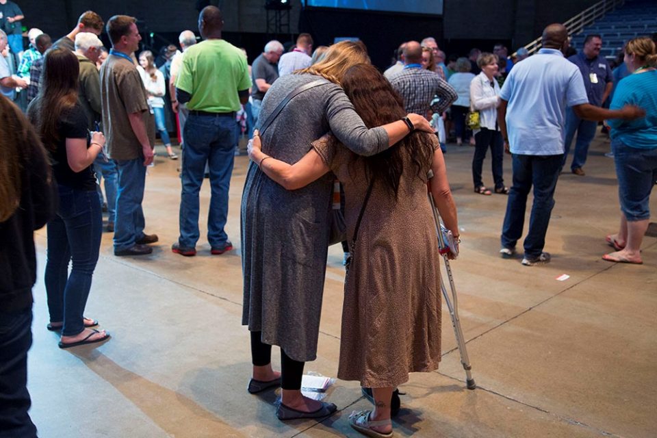 Two women pray with arms around each other