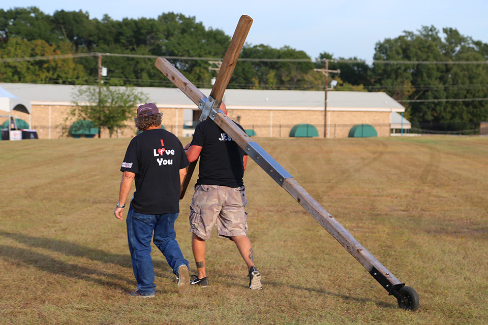 Man carrying cross and a man walking beside him