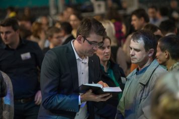 Counselor showing Bible verse to man during invitation