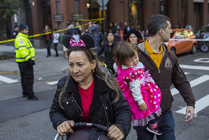 Woman in Minnie Mouse ears pushing stroller. Man behind her carrying little girl dressed as Minnie Mouse.