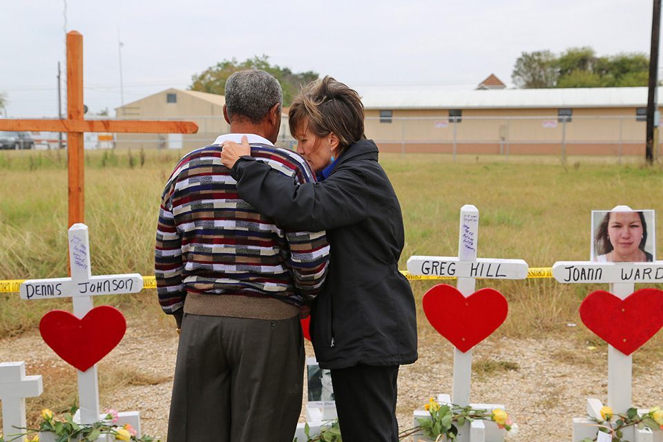 Chaplain praying with man in front of crosses representing shooting victims