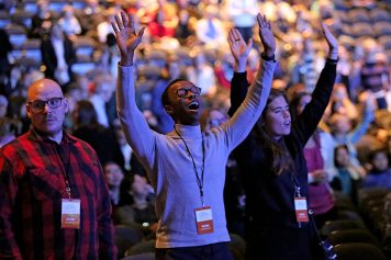 Counselor Gilles Gatete's arms raised in worship