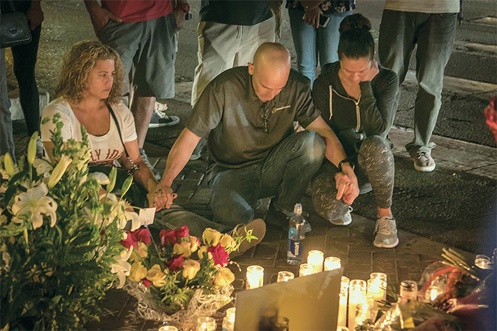 People kneeling, holding hands, praying at Las Vegas memorial for victims