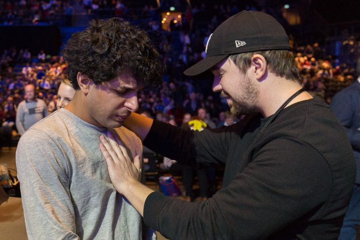 Young man with hand on shoulder of another young man, praying