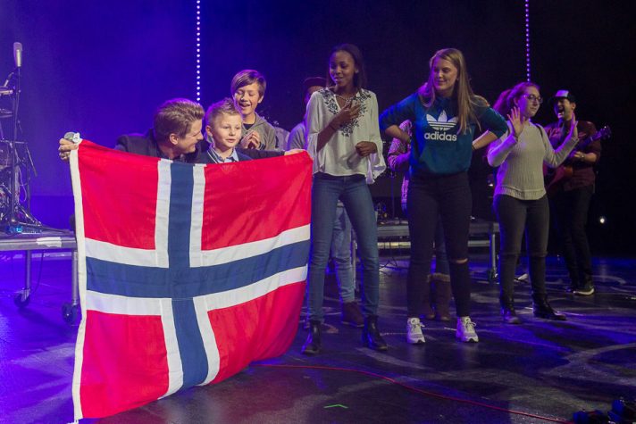 Josh Havens holding Norwegian flag in front of young boy, youth behind them